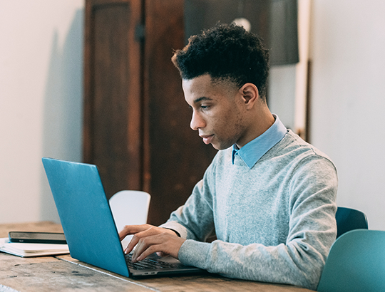 A boy is typing in the laptop